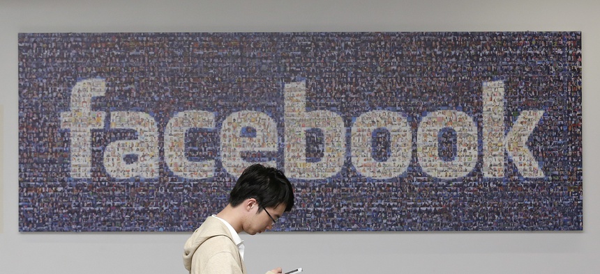 A man walks past a Facebook sign at the company's campus in Menlo Park, Calif., on June 11, 2014.