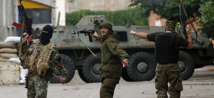 Pro-Russian fighters in the city of Donetsk dance and fire their weapons in the air in a Ukrainian military unit recently captured by their forces, on June 27, 2014.
