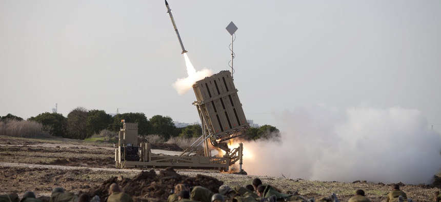 Israeli soldiers take cover as an Iron Dome battery fires a rocket near the city of Ashrod, on November 19, 2012.