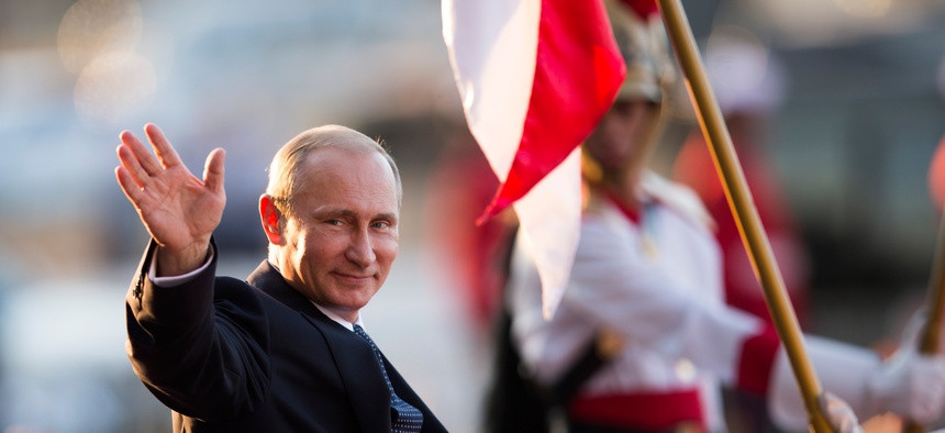 Russia's President Vladimir Putin waves to photographers as he leaves the Itamaraty Palace after the BRICS Summit in Brasilia, Brazil, July 16, 2014.