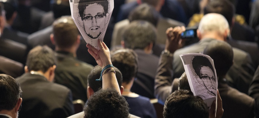 Participants at an internet conference in Sao Paolo hold up pictures of Edward Snowden during a session.