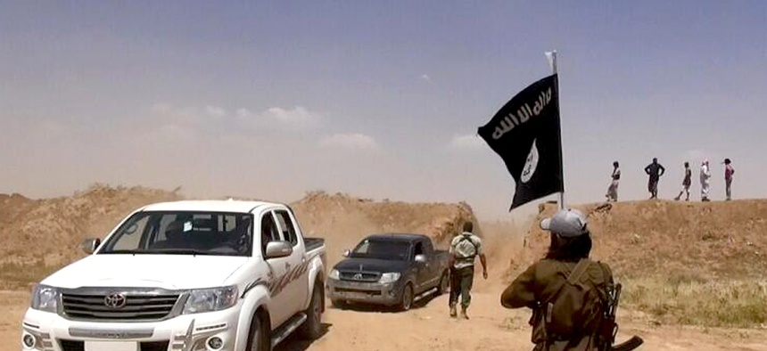ISIL insurgents wave flags as they cross the border between Syria and Iraq.