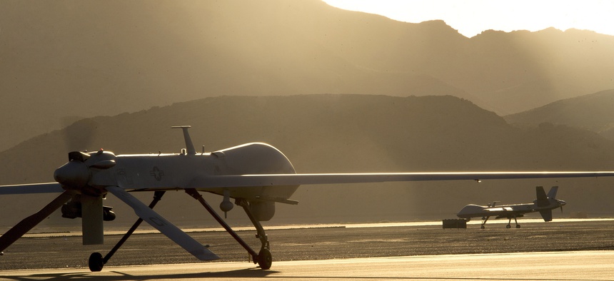 An MQ-1B Predator and an MQ-9 Reaper taxi to the end of a runway at Creech Air Force Base in preparation for takeoff, on June 13, 2014.