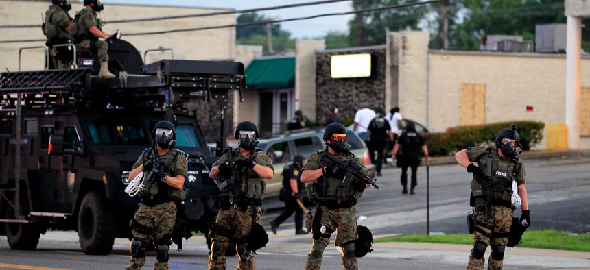Police wearing riot gear try to disperse a crowd, Aug. 11, 2014, in Ferguson, Mo.