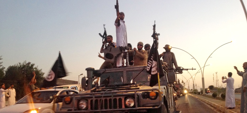 Fighters from the Islamic State ride in an armored vehicle down a main road in the city of Mosul, Iraq.