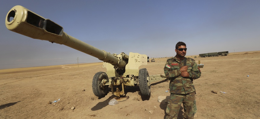 A Kurdish peshmerga fighter stands next to a firearm in Mahmoudiyah, Iraq, on October 1, 2014.