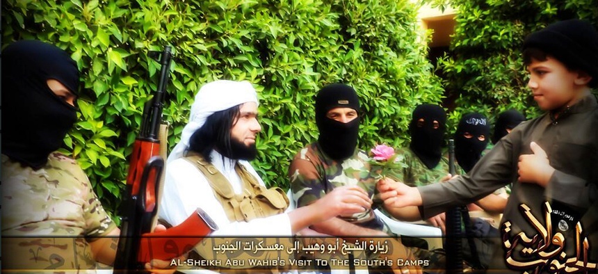 This Screen grab from an Islamic State affiliated Twitter account, taken Sept. 20, 2014, purports to show senior military commander Abu Wahib handing a flower to a child while in southern Iraq, as part of the group's broad social media campaign.