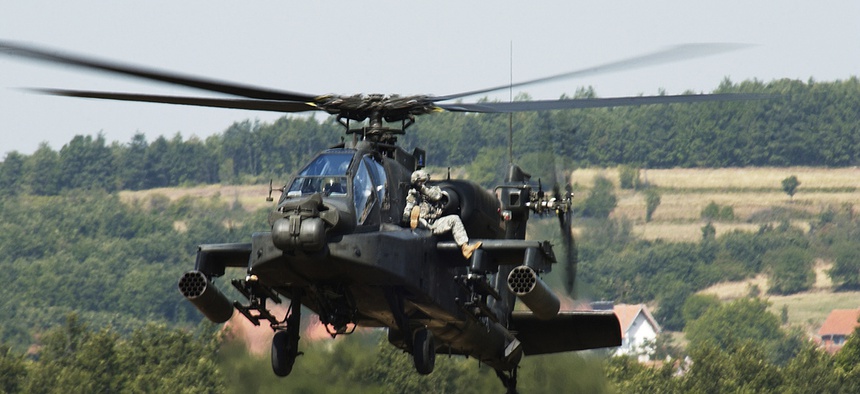Two soldiers from the Multi-National Task Force ride on an Ah-64 Apache helicopter during an exercise at Camp Bondsteel, Kosovo.