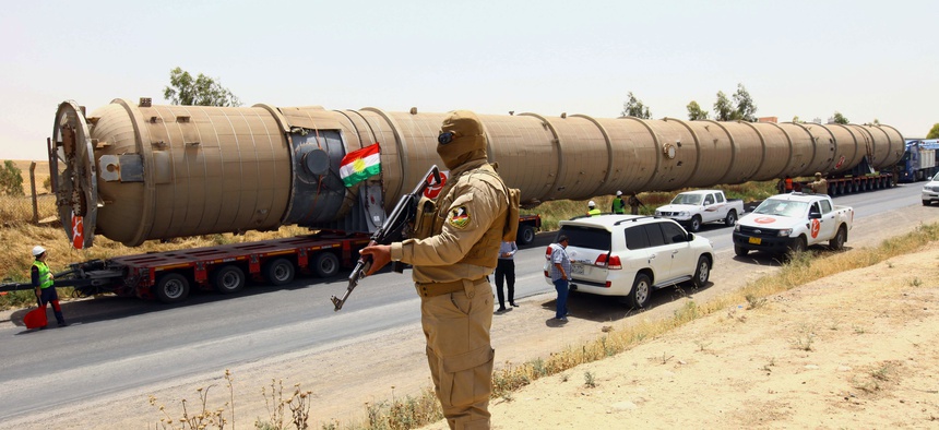 A Kurdish peshmerga fighter stands guard as new equipment arrives at the Kalak refinery on the outskirts of Irbil, Iraq.