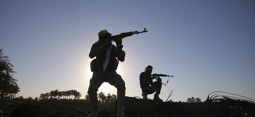 Iraqi Shiite fighters aim their weapons during clashes southwest of Baghdad, Iraq, on October 7, 2014.
