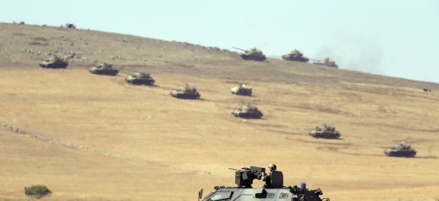 Turkish tanks and armored vehicles hold their positions on a hilltop outside of Suruc, at the Turkey-Syria border, on October 6, 2014.