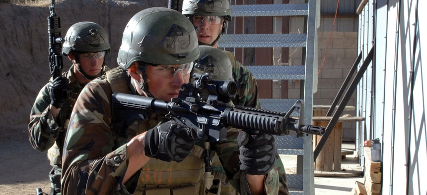 A team of four SEAL trainees prepare to breach a room during a training exercise.
