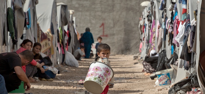 A Syrian Kurdish refugee child from the Kobani area holds a bucket at a refugee camp in Suruc, near the Turkey-Syria border, Nov. 2, 2014. Kobani, also known as Ayn Arab, and its surrounding areas, has been under assault by ISIS since mid-September.
