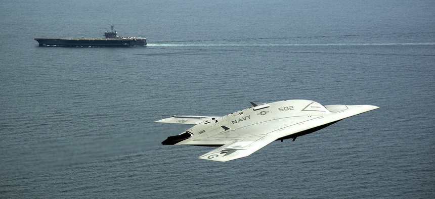 An X-47B demonstrator flies near the USS George H.W. Bush.