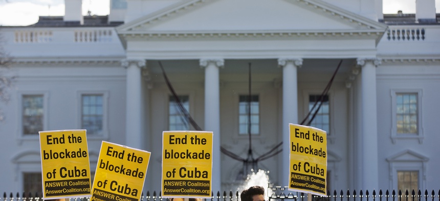People from the ANSWER Coalition hold signs urging the U.S. to "End the blockade of Cuba," during a demonstration outside of the White House on Decmeber 17, 2014.