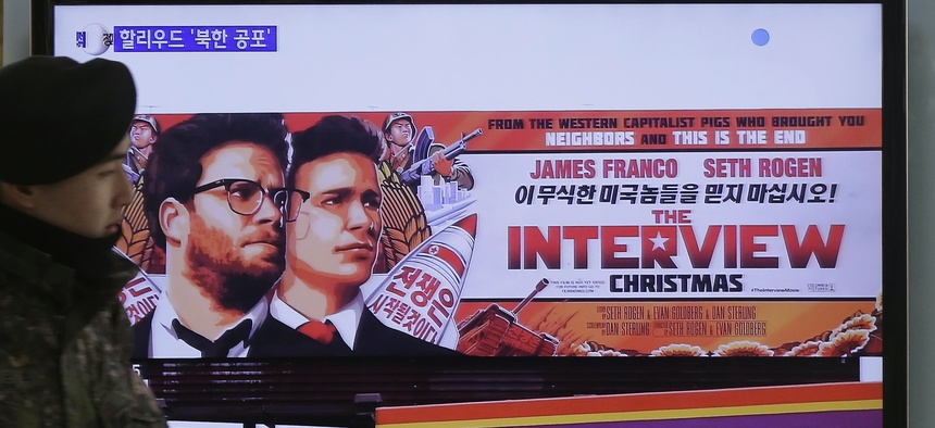 A South Korean army soldier walks near a screen showing the trailer of The Interview.