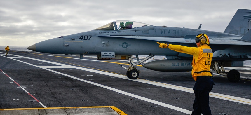 A sailor aboard the USS John C. Stennis direcs an F/A 18 during a training exercise, on December 10, 2014.