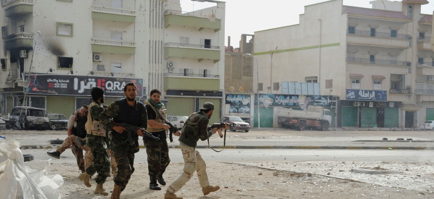 Libyan military soldiers run to take cover during clashes with Islamic extremist militias in Benghazi, Libya, Oct. 30, 2014.