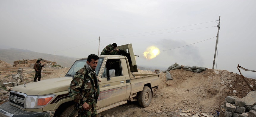 A Kurdish peshmerga fighter fires a weapon towards an Islamic State Group position 500 meters, or half a mile away, overlooking the town of Sinjar northern Iraq, jan. 29, 2015.