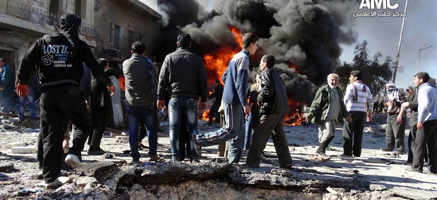 Syrian citizens gather near flames caused by a government forces warplane attack in al-Bab neighborhood of Aleppo, Syria, on Feb. 1, 2014.