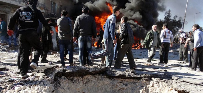 Syrian citizens gather near flames caused by a government forces warplane attack in al-Bab neighborhood of Aleppo, Syria, on Feb. 1, 2014.