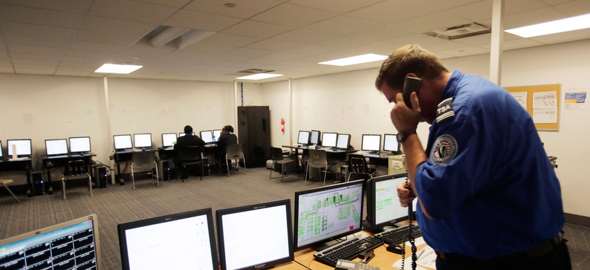 A Transportation Security Administration officer watches computer monitors that display luggage as it is tracked through various security screening measures, Thursday, Oct. 30, 2014 at John F. Kennedy International Airport in New York.
