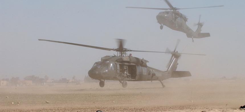 Two U.S. Army UH-60 Black Hawk helicopters blow up clouds of dust as they come into a landing zone in Samarra, Iraq.