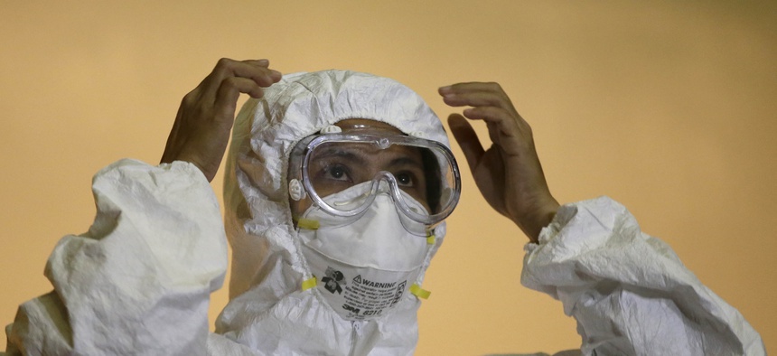 A health worker in the Philippines shows the proper way to wear an "Ebola suit" during a media tour of the Research Institute for Tropical Medicine facility to show the Government's readiness in the still Ebola-free country Tuesday, Oct. 21, 2014.