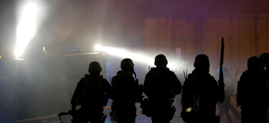 Police advance to disperse the crowd after firing tear gas outsidethe Ferguson city hall, on Tuesday, Nov. 25, 2014, in Ferguson, Mo.