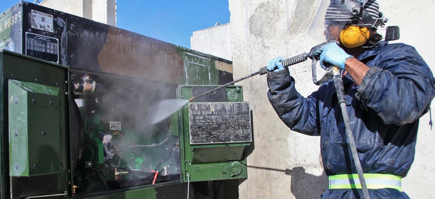 A private contractor sprays water to clean parts of a generator at Forward Operating Base Shank, Logar province, Afghanistan, March 14, 2012.
