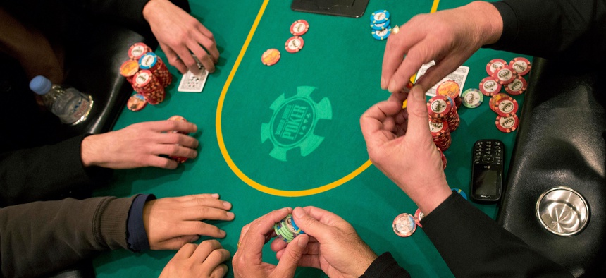 In this Feb. 27, 2013 photo, poker players cast their bets during a hand of Texas Hold 'em at the poker room at Caesar's Palace in Las Vegas.