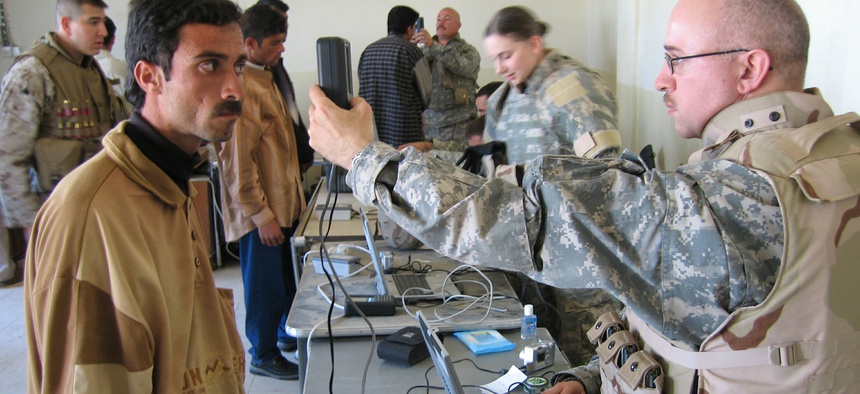 An unidentified U.S. soldier conducts an iris scan on an Iraqi man during an Iraqi army recruiting drive in the city of Ramadi on Monday March 27, 2006.