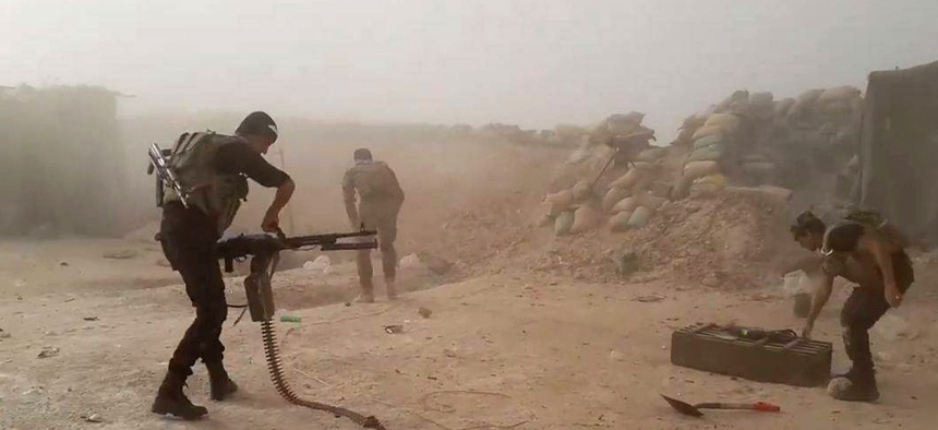 In this image taken Friday, May 29, 2015, Iraqi anti-terrorism forces battle with Islamic State group extremists as they defend their base against Islamic State group extremist attack outside Fallujah.