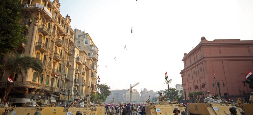 Egyptian military helicopters fly overhead as army soldiers stand guard at an entrance to Tahrir Square, in Cairo, Egypt., on October 6, 2013.