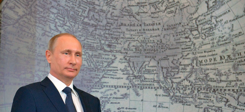 Russian President Vladimir Putin holds an award during a meeting of Russian Geographical Society in St Petersburg, Russia, Monday, April 27, 2015.