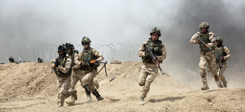Iraqi soldiers run through a breach in a berm while training at Camp Taji, Iraq, on June 2, 2015.