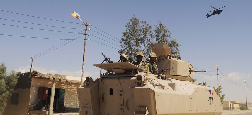 Egyptian Army soldiers patrol in an armored vehicle backed by a helicopter gunship during a sweep through villages in Sheikh Zuweyid, north Sinai, Egypt, on May 12, 2013.