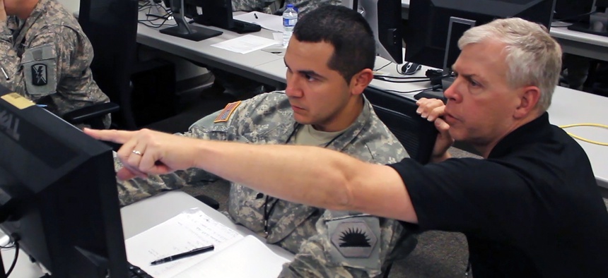 A California National Guard soldier assists another analyst during a simulated virus attack at 2014 Cyber Shield exercise.