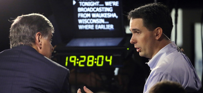Wisconsin Gov. Scott Walker, right, gives a broadcast interview after announcing that he is running for the 2016 Republican presidential nomination at the Waukesha County Expo Center, Monday, July 13, 2015, in Waukesha, Wis.