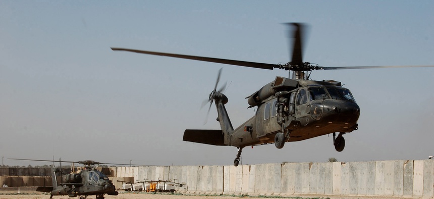 A Blackhawk and Apache helicopter from the 3rd and 4th Battalions prepare to depart Camp Dolby during an operation six miles south of Baghdad.