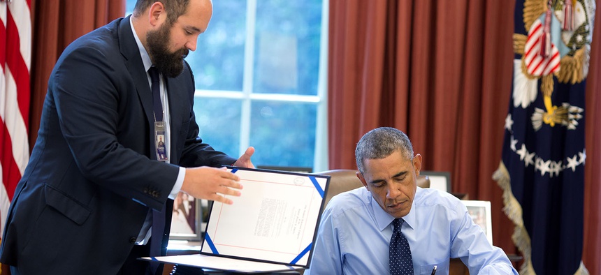 President Barack Obama signs bills in the Oval Office in 2014.