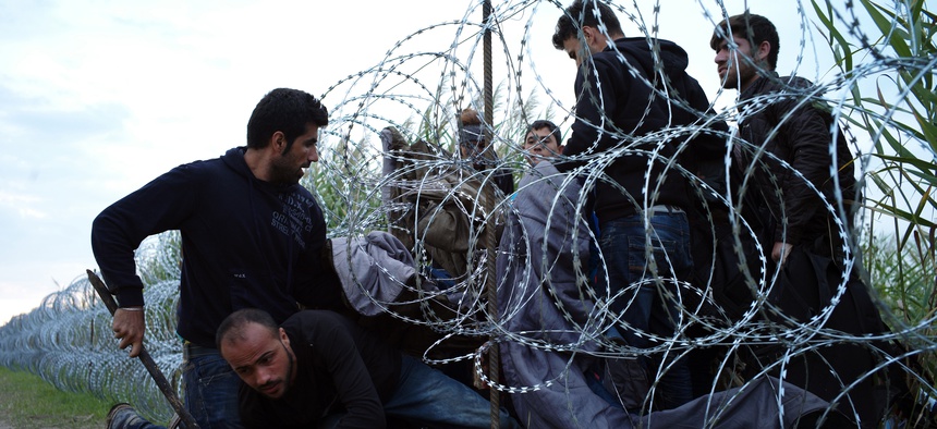 Syrian refugees cross into Hungary underneath the border fence on the Hungarian - Serbian border near Roszke, Hungary.