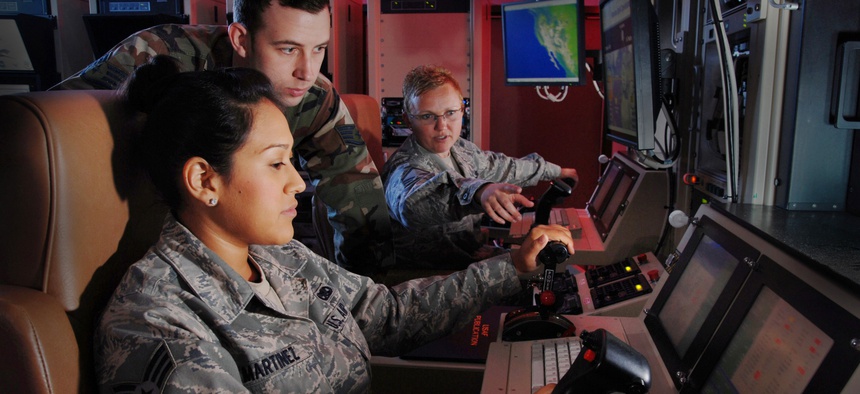 USAF Master Sgt. Jennifer Oberg explains the features of a ground control station to Staff Sgt. Jason Avera and Senior Airman Raquel Martinez.