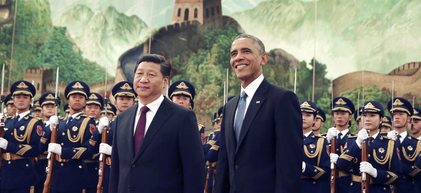 In this Nov. 12, 2014 file photo, U.S. President Barack Obama, right smiles as a group of children wave flags and flowers during a welcome ceremony held by Chinese President Xi Jinping at the Great Hall of the People in Beijing, China.