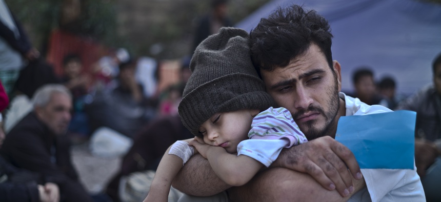 A Syrian refugee child sleeps on his father's arms while waiting at a resting point to board a bus, after arriving on a dinghy from the Turkish coast to the northeastern Greek island of Lesbos, Sunday, Oct. 4 , 2015.