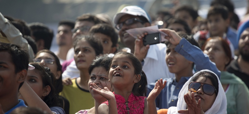 On the day India's air force chief announced women would be allowed to become fighter pilots, a girl looks skyward to watch the military air show at Air Force Day at Hindon Air Force base near New Delhi, India, Oct. 8, 2015.