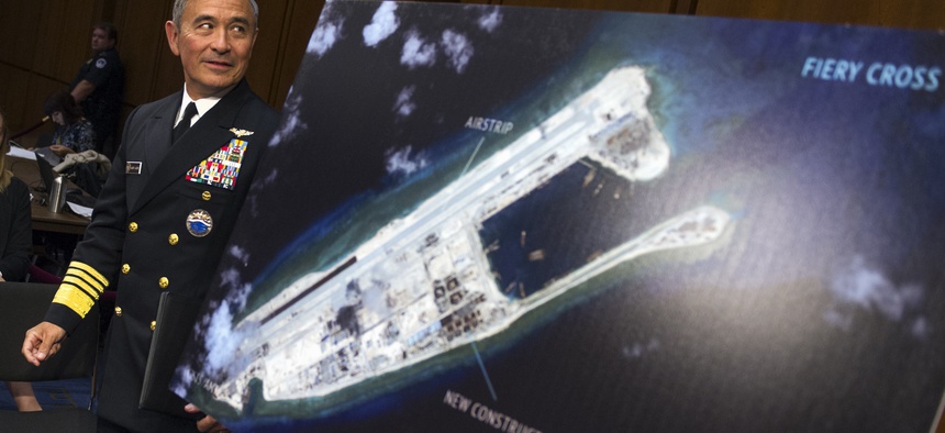 Adm. Harry B. Harris, Jr. of U.S. Navy Commander, U.S. Pacific Command walks past a photograph showing an island that China is building on the Fiery Cross Reef in the South China Sea, as the prepares to testify on Capitol Hill, Sept. 17, 2015.