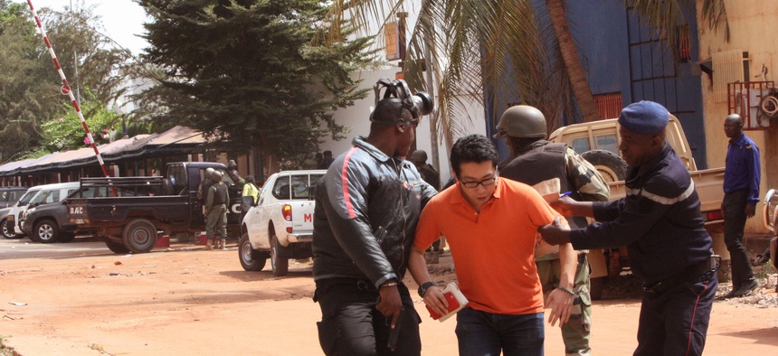 Mali trooper assist a hostage, centre, to leave the scene, from the Radisson Blu hotel to safety after gunmen attacked the hotel in Bamako, Mali, Friday, Nov. 20, 2015.