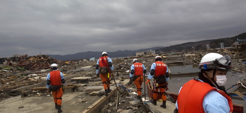 Japanese recovery officials search through the ruins of the leveled city of Minamisanriku, in northeastern Japan, Tuesday March 15, 2011.