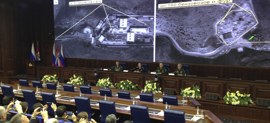 Russian top military officials speak to the media in front of an aerial images they say are oil trucks near Turkey’s border with Syria displayed by the Russian Defense Ministry at a briefing in Moscow, Russia, Wednesday, Dec. 2, 2015.